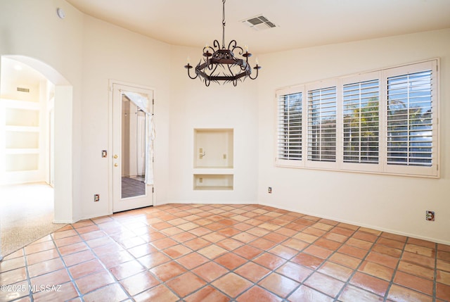 tiled spare room featuring built in shelves, vaulted ceiling, and a notable chandelier