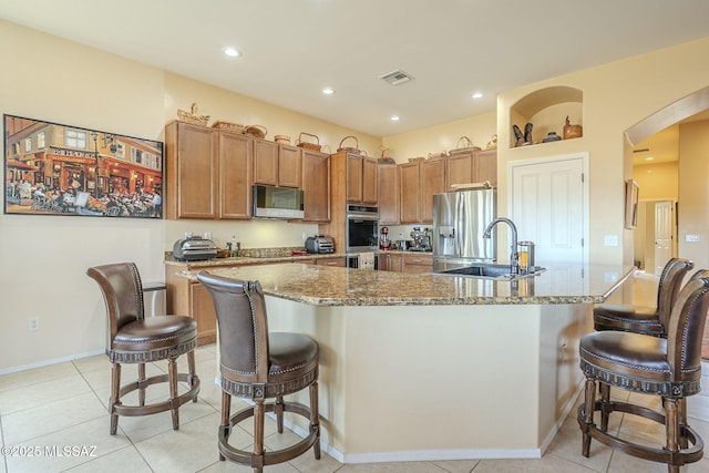 kitchen with stainless steel appliances, a breakfast bar area, and a large island with sink