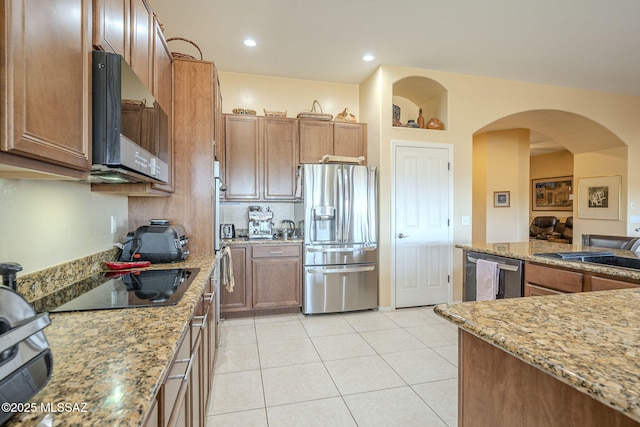 kitchen with light stone countertops, light tile patterned flooring, appliances with stainless steel finishes, and sink