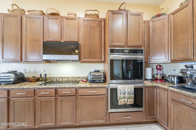 kitchen featuring light tile patterned floors, double oven, light stone counters, black electric stovetop, and ventilation hood