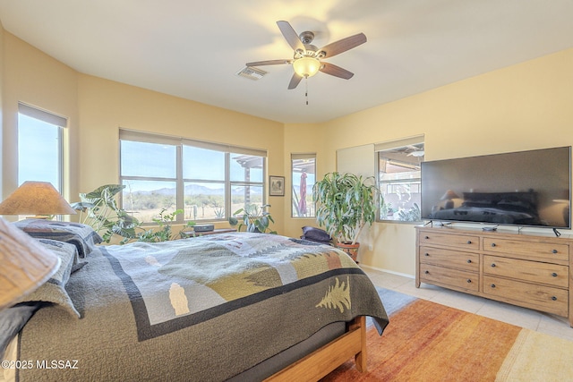 tiled bedroom with ceiling fan and multiple windows