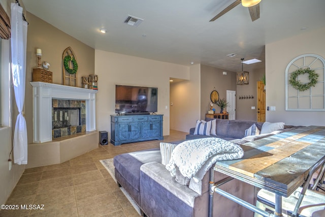 living room with a tile fireplace, light tile patterned floors, and ceiling fan