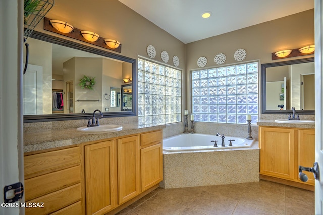 bathroom with a relaxing tiled tub, tile patterned floors, and vanity