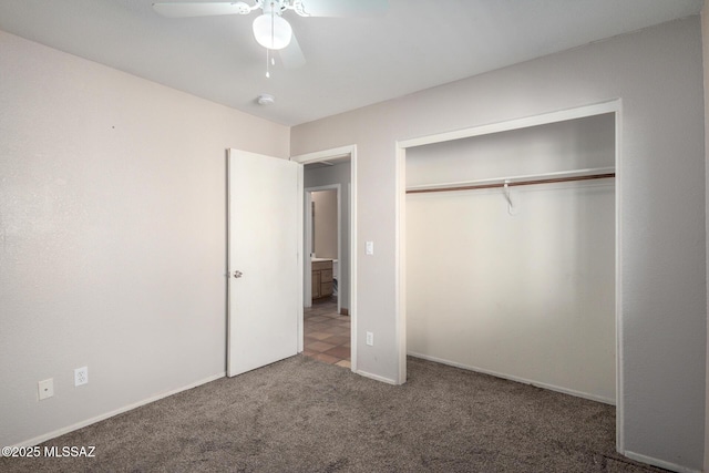 unfurnished bedroom with dark colored carpet, ceiling fan, and a closet