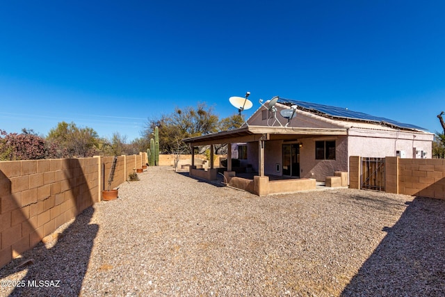 rear view of house featuring a patio area and solar panels