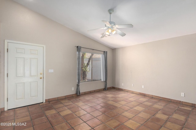 empty room with dark tile patterned flooring, vaulted ceiling, and ceiling fan
