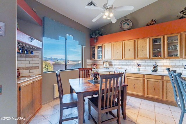 kitchen featuring vaulted ceiling, ceiling fan, light tile patterned floors, and backsplash