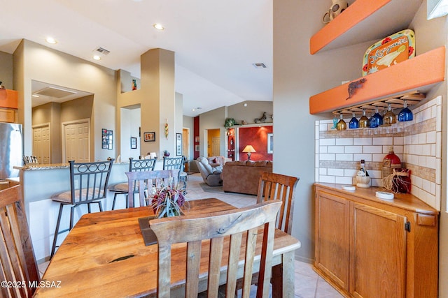 tiled dining area featuring vaulted ceiling