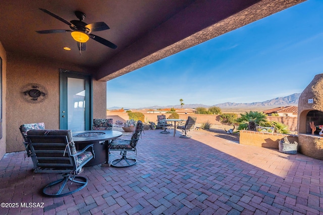 view of patio / terrace with ceiling fan, an outdoor fireplace, and a mountain view