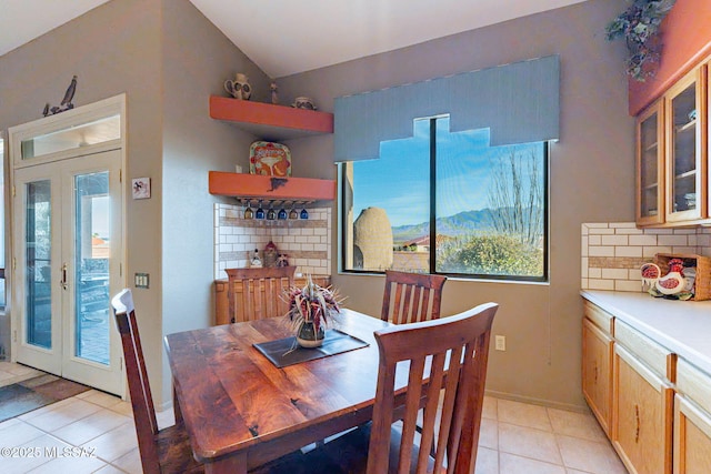 tiled dining area with lofted ceiling and french doors