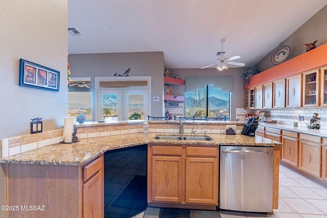 kitchen with stainless steel dishwasher, light stone countertops, sink, and backsplash