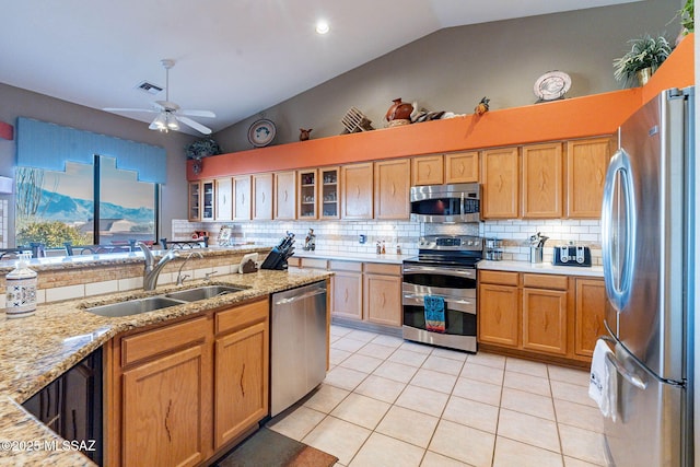 kitchen with sink, backsplash, light tile patterned floors, stainless steel appliances, and light stone countertops