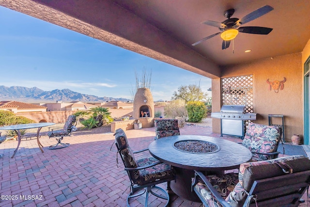 view of patio featuring a mountain view, a large fireplace, a grill, and ceiling fan