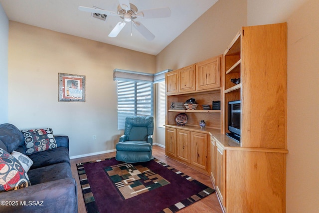 living room featuring light hardwood / wood-style flooring, ceiling fan, and vaulted ceiling