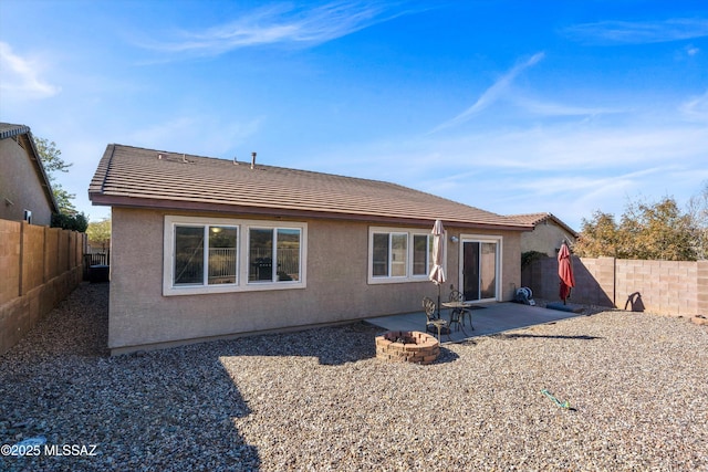 back of property with a patio and a fire pit