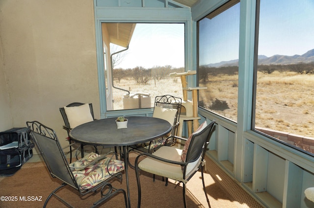 sunroom / solarium with lofted ceiling, a mountain view, and a wealth of natural light