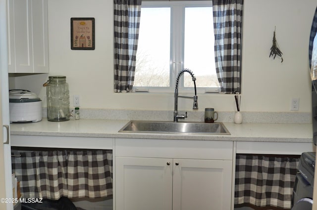 kitchen featuring washer / dryer, light stone countertops, sink, and white cabinets