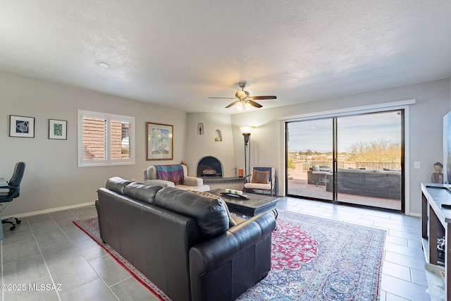 living room with ceiling fan, a fireplace, a textured ceiling, and a wealth of natural light