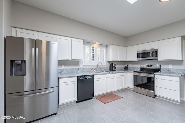 kitchen with appliances with stainless steel finishes, sink, white cabinets, and light stone counters