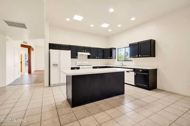 kitchen featuring white appliances, a center island, sink, and light tile patterned floors