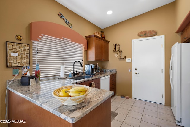 kitchen featuring sink, light stone counters, light tile patterned floors, kitchen peninsula, and white appliances