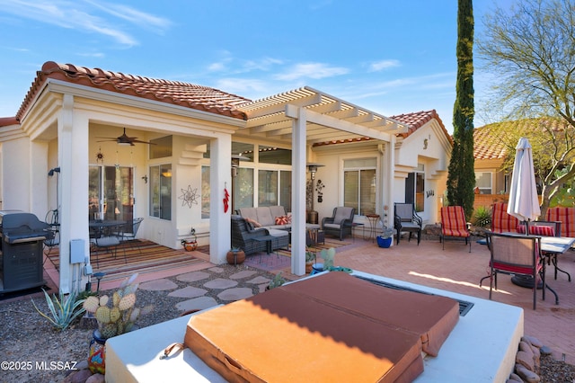 rear view of property with a covered hot tub, a pergola, ceiling fan, an outdoor hangout area, and a patio