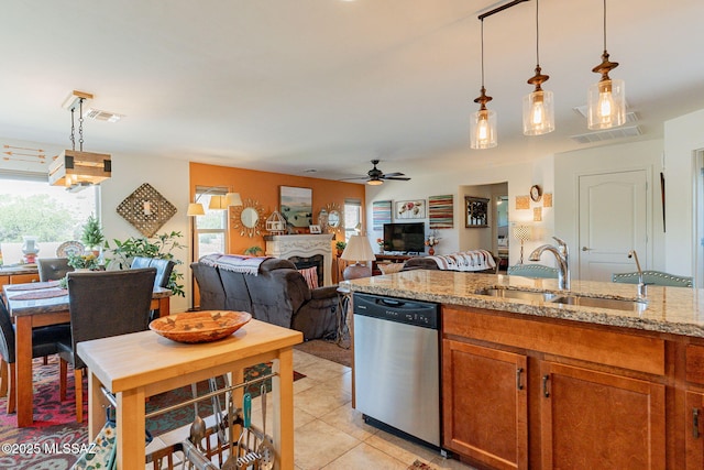 kitchen with light tile patterned flooring, decorative light fixtures, dishwasher, sink, and light stone countertops