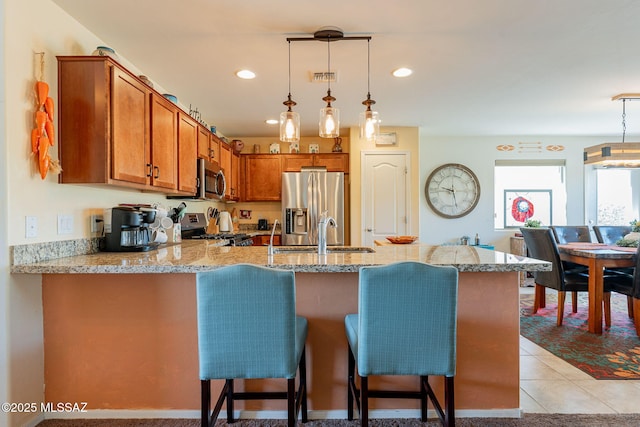 kitchen featuring pendant lighting, sink, kitchen peninsula, and appliances with stainless steel finishes