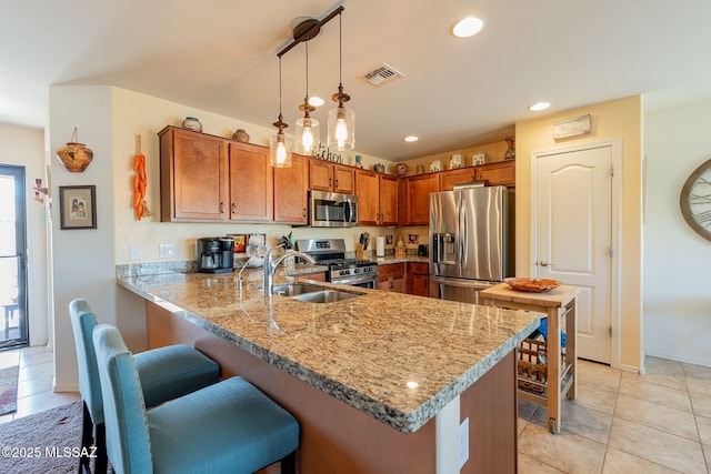 kitchen with light stone counters, decorative light fixtures, stainless steel appliances, and kitchen peninsula