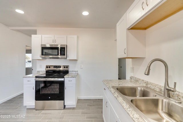 kitchen featuring light stone counters, appliances with stainless steel finishes, sink, and white cabinets