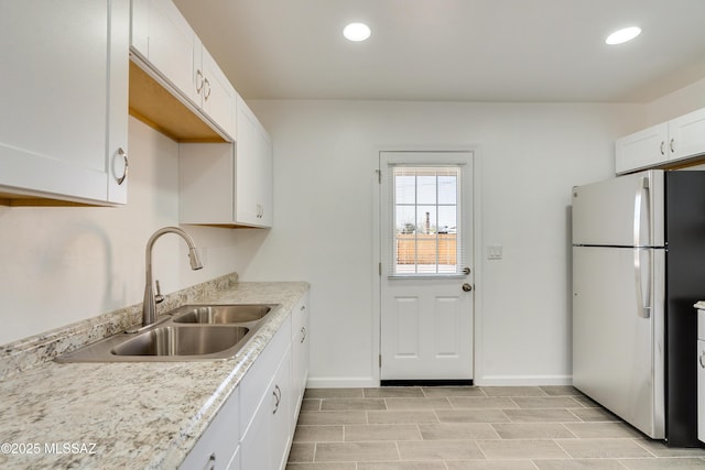 kitchen featuring white cabinetry, sink, and stainless steel refrigerator