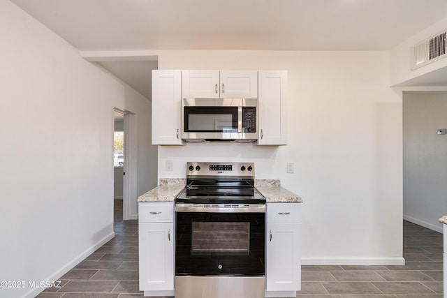 kitchen featuring stainless steel appliances, white cabinets, and light stone counters