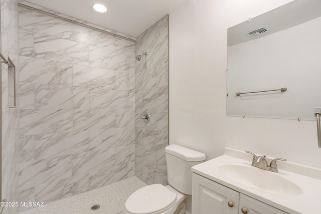 bathroom with tiled shower, vanity, and toilet