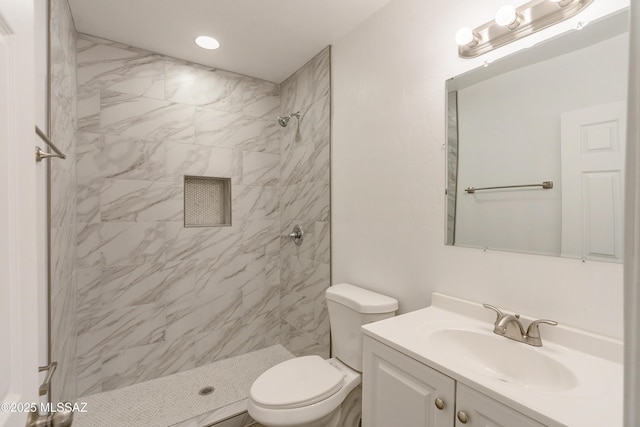 bathroom with vanity, toilet, and a tile shower