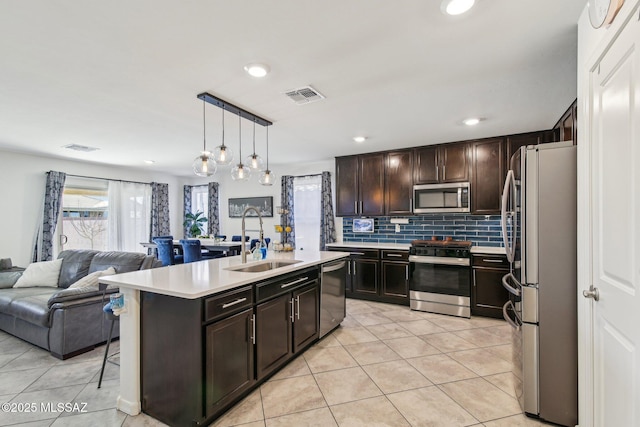 kitchen featuring light tile patterned floors, a sink, open floor plan, light countertops, and appliances with stainless steel finishes