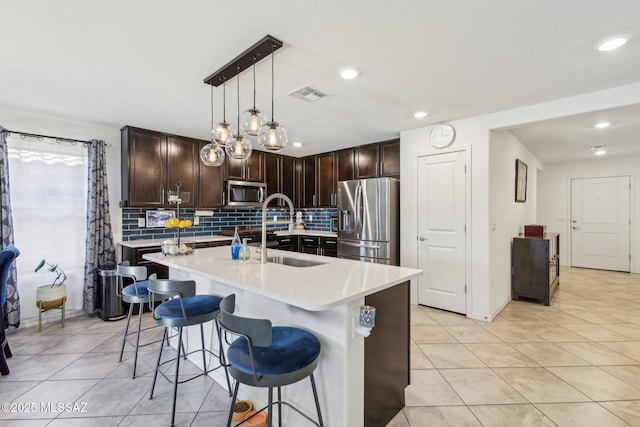 kitchen featuring visible vents, appliances with stainless steel finishes, light countertops, dark brown cabinets, and a sink