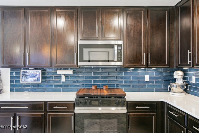 kitchen with dark brown cabinets, stainless steel microwave, range with gas cooktop, and backsplash