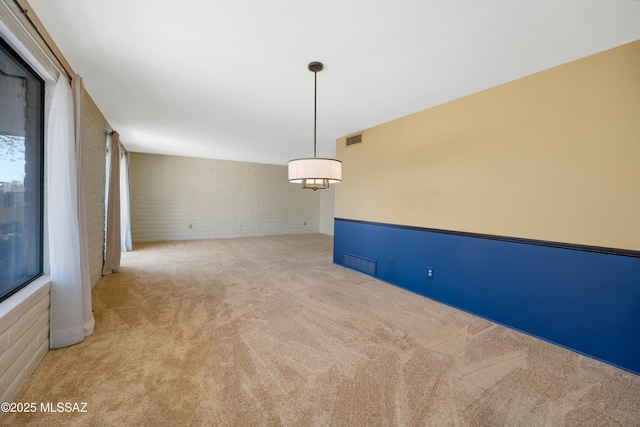 carpeted spare room with brick wall