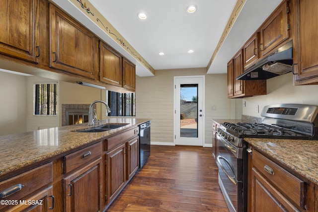 kitchen with black dishwasher, sink, dark hardwood / wood-style flooring, double oven range, and light stone countertops