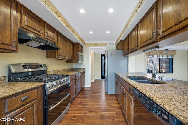 kitchen featuring stainless steel appliances, light stone countertops, sink, and dark wood-type flooring