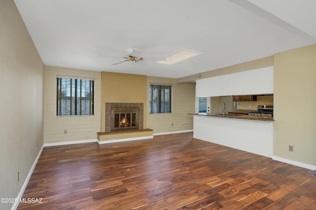 unfurnished living room featuring ceiling fan, sink, and dark hardwood / wood-style flooring