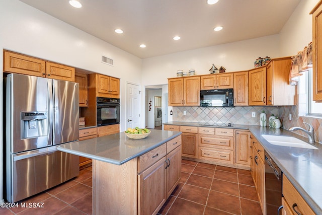 kitchen featuring visible vents, a sink, black appliances, dark tile patterned floors, and tasteful backsplash