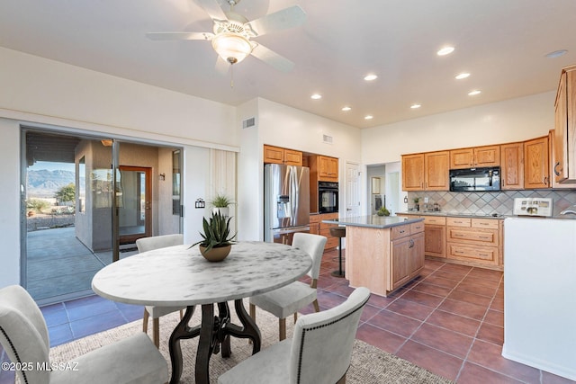 kitchen with a kitchen island, dark tile patterned flooring, recessed lighting, black appliances, and tasteful backsplash