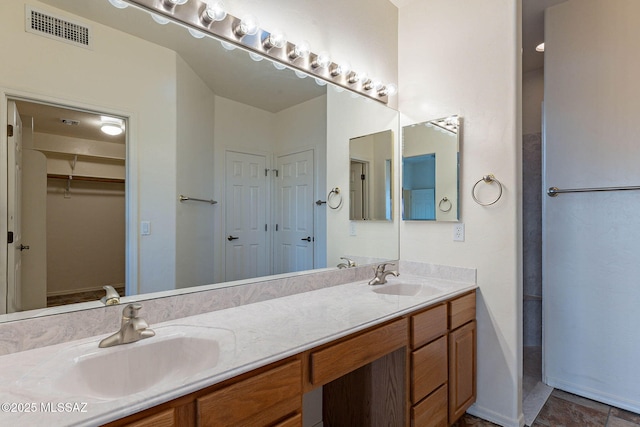 full bathroom with double vanity, visible vents, a walk in closet, and a sink