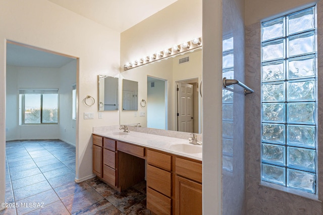 full bathroom with double vanity, visible vents, baseboards, and a sink