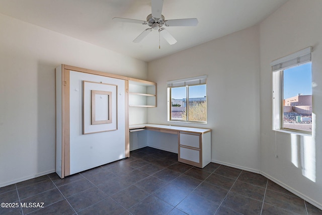 unfurnished office with baseboards, a ceiling fan, and built in desk