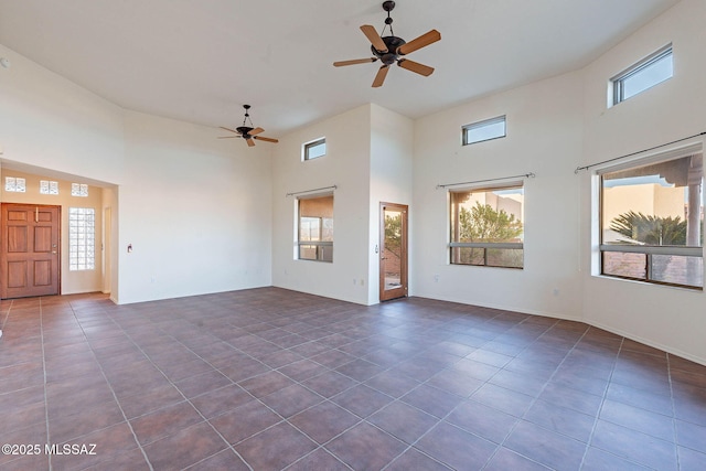 spare room with a high ceiling, ceiling fan, and dark tile patterned flooring