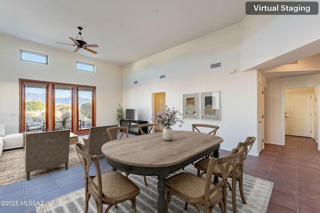 tiled dining room featuring visible vents, a towering ceiling, and a ceiling fan