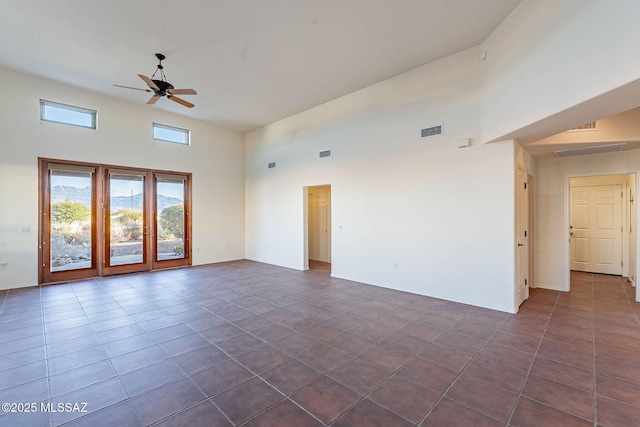 empty room featuring a ceiling fan, visible vents, and a towering ceiling