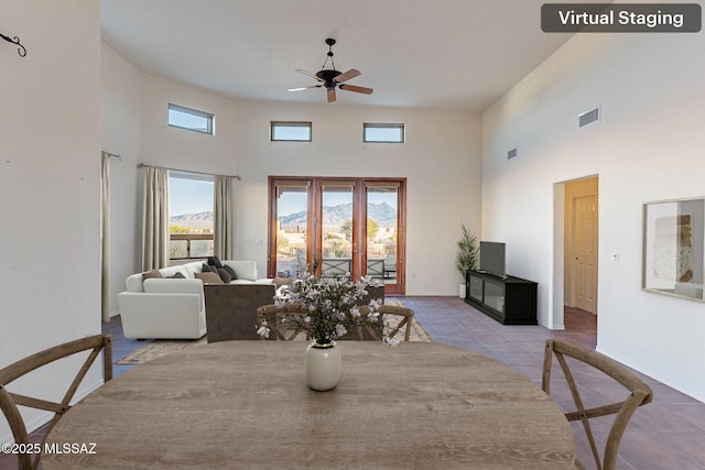 tiled dining room with visible vents, baseboards, a high ceiling, and ceiling fan